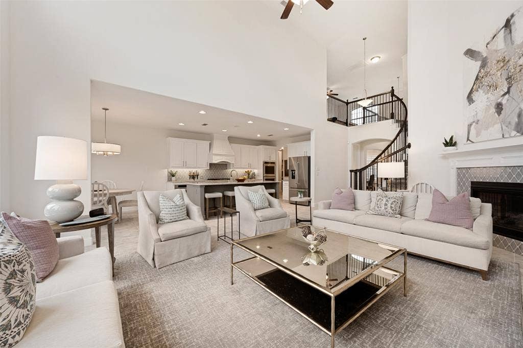 131 Darian Drive, Prosper, TX 75078 High ceilings, open-concept design, fireplace with tile surround, spiral staircase with wrought iron railing, and a kitchen with an island and stainless steel appliances