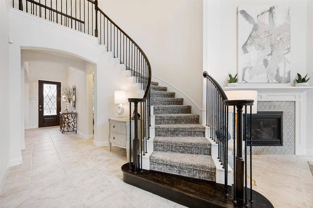 131 Darian Drive, Prosper, TX 75078 Curved staircase with iron balusters, carpeted treads, and wood handrail