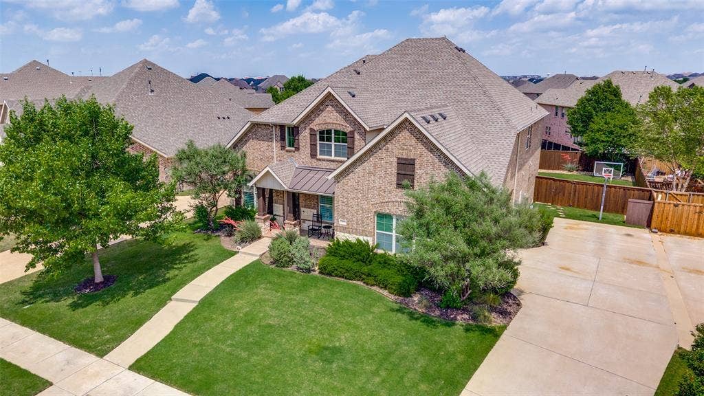 131 Darian Drive, Prosper, TX 75078 Brick exterior with a covered entry, mature landscaping, and a concrete driveway