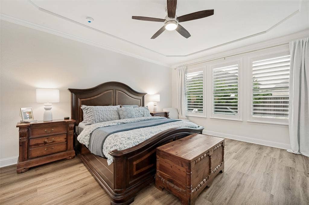 131 Darian Drive, Prosper, TX 75078 Tray ceiling with crown molding, ceiling fan, three windows with plantation shutters, wood-finish flooring, and white baseboards