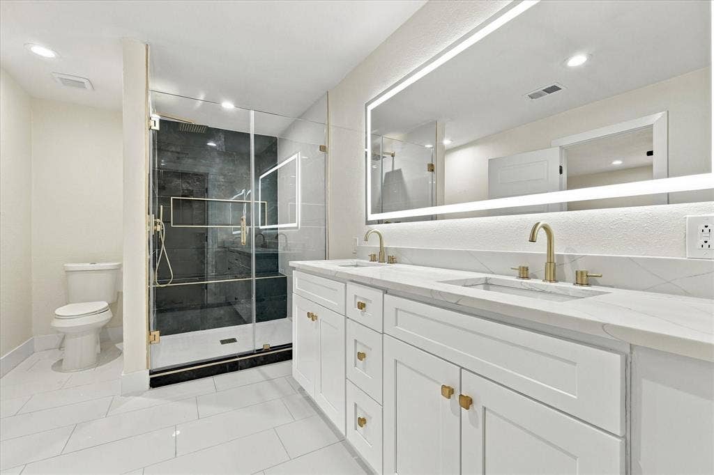 Walk-in shower with gold-finish fixtures, a built-in bench, a recessed niche, and contrasting tile finishes