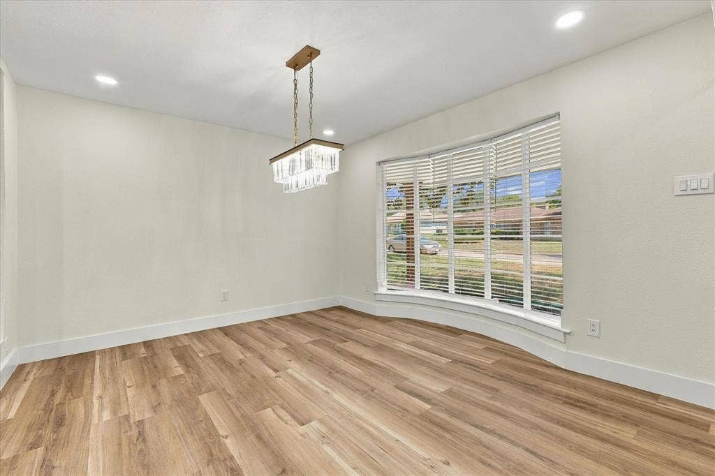 Wood-finish flooring throughout, white cabinetry with gold-tone hardware, white subway tile backsplash, stainless steel dishwasher, and recessed ceiling lighting