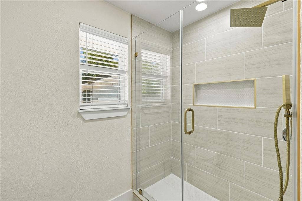 White vanity with shaker-style cabinetry, a white countertop featuring subtle veining, and a black-finish faucet