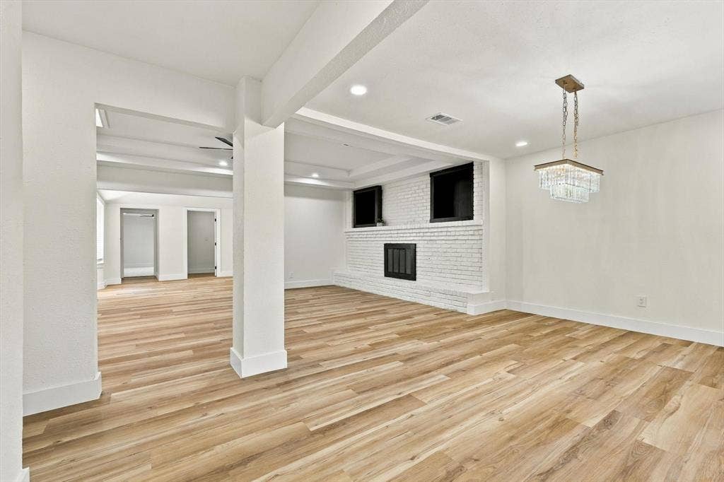 Spacious living area featuring wood-finish flooring, a white brick fireplace with a black grate, a ceiling fan, and recessed lighting