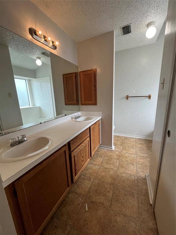 724 Ballard Street, Cedar Hill, TX 75104 Bathroom featuring tile patterned floors, a textured ceiling, and dual bowl vanity