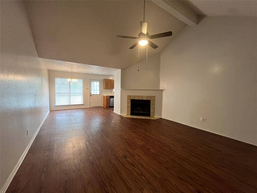 724 Ballard Street, Cedar Hill, TX 75104 Unfurnished living room featuring beam ceiling, ceiling fan with notable chandelier, dark hardwood / wood-style flooring, a tile fireplace, and high vaulted ceiling