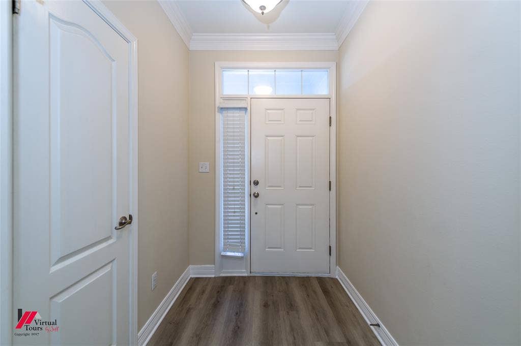 Entry featuring a six-panel door with transom and sidelight, crown molding, and wood-finish flooring