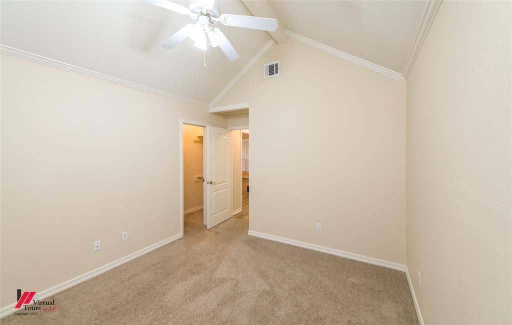 Vaulted ceilings, neutral carpeted flooring, and a white ceiling fan with integrated lighting
