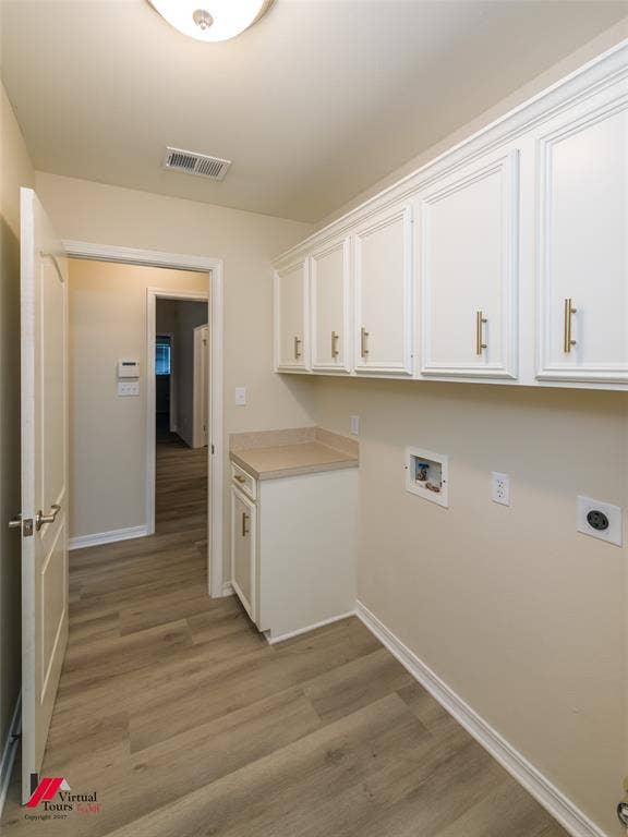 Laundry area featuring white shaker-style cabinetry with gold-toned hardware, solid surface countertop, and wood-finish flooring