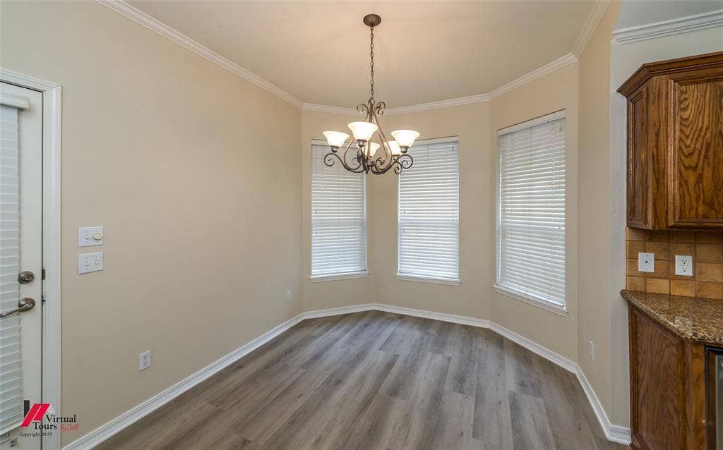 Bay window featuring wood-finish flooring, crown molding, and a decorative multi-arm chandelier