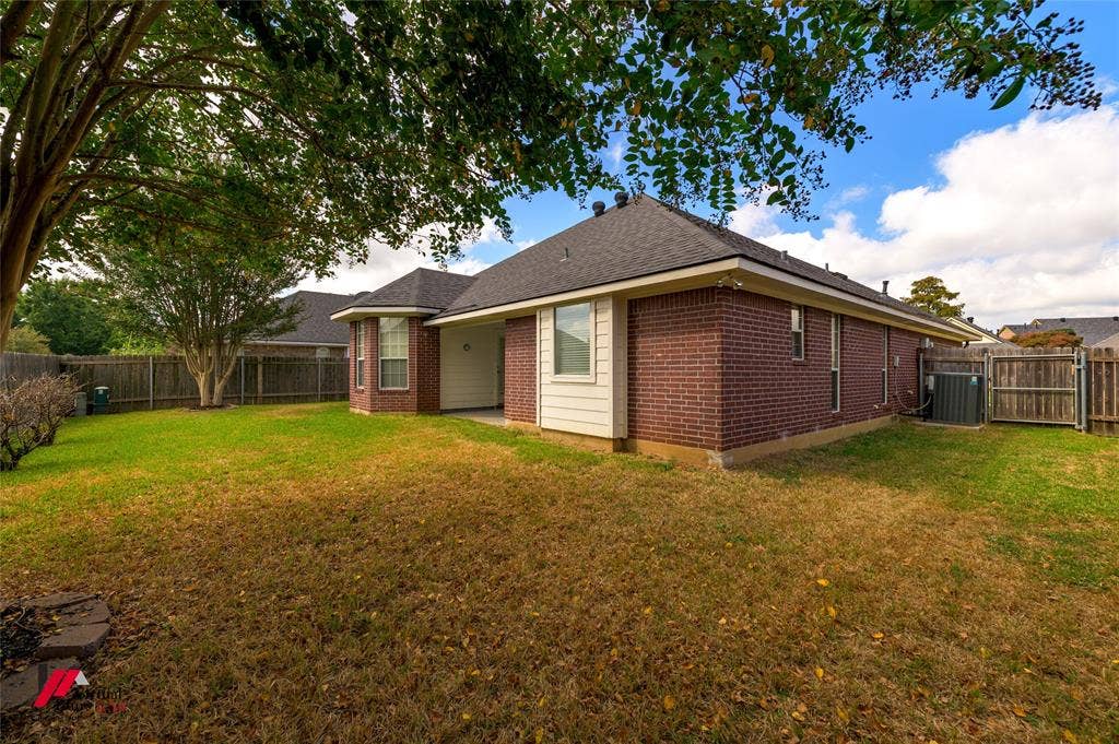 Brick exterior, hipped roof, covered patio, wood fencing, and expansive lawn