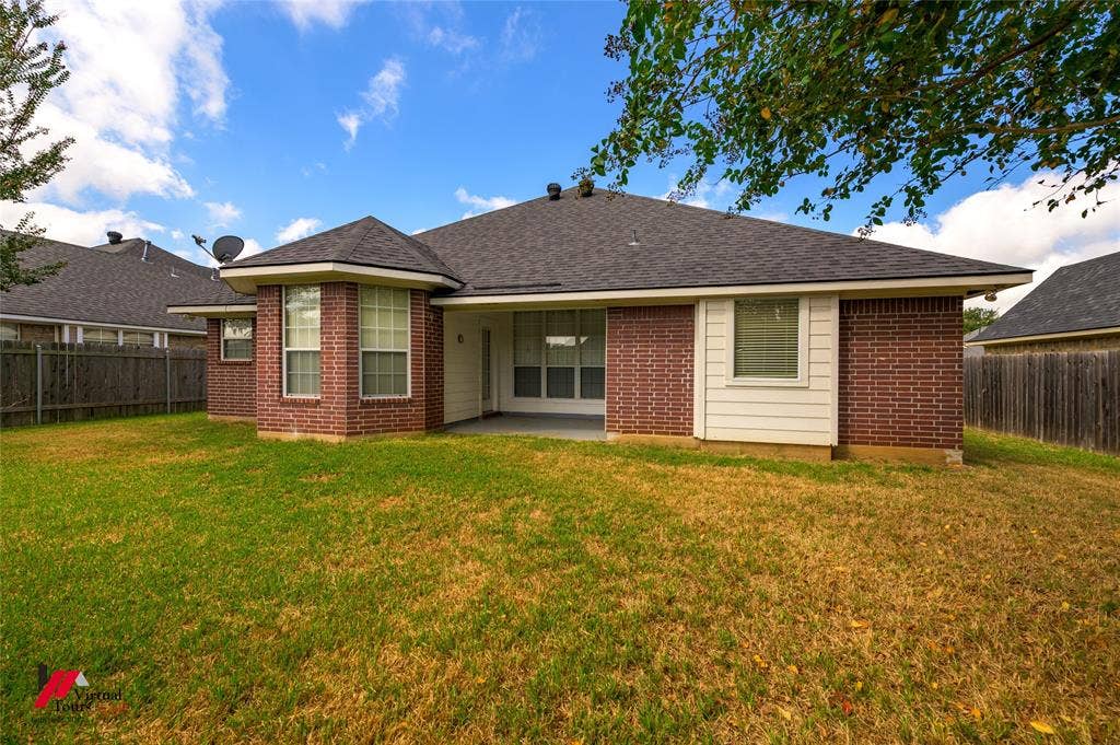 Rear exterior featuring a brick and siding facade, a covered patio, and wood privacy fencing