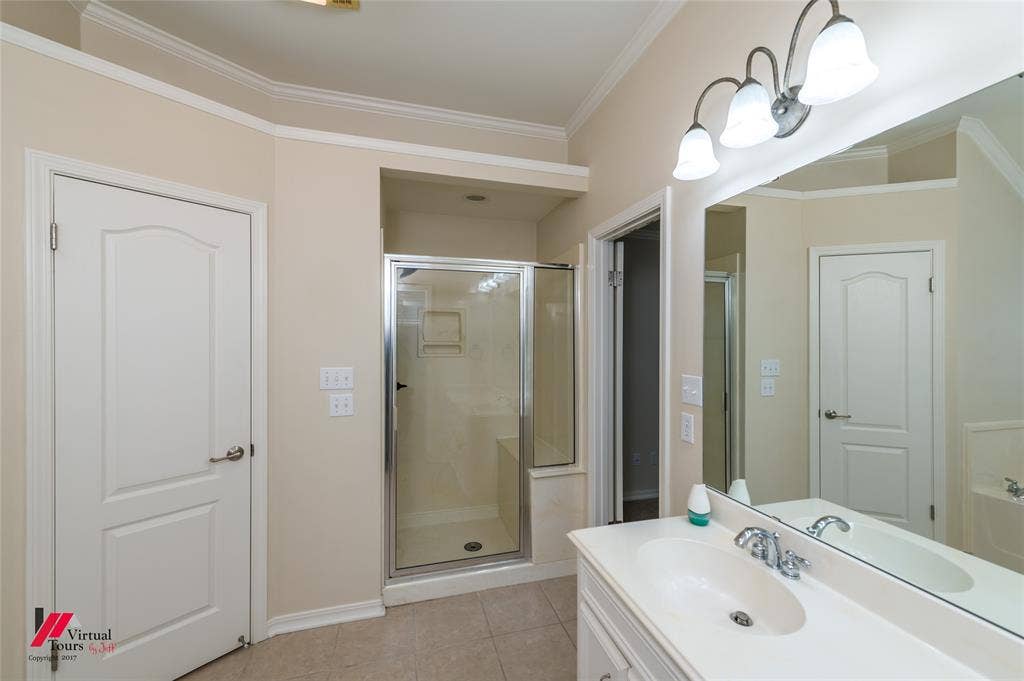 Vanity featuring a white countertop with an integrated oval basin, chrome faucet, wall-mounted mirror, and three-light overhead fixture