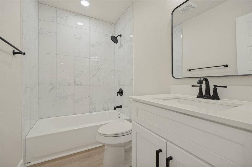 White vanity with an integrated sink, matte black faucet, and a rectangular framed mirror