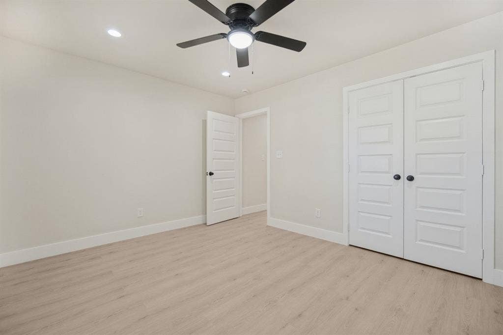Recessed ceiling lighting with a ceiling fan, light wood-finish flooring, and white paneled doors
