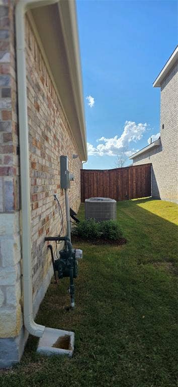 3904 Malachite Drive, Celina, TX 75009 Brick and stone facade with a brown privacy fence, featuring a manicured lawn and an HVAC unit