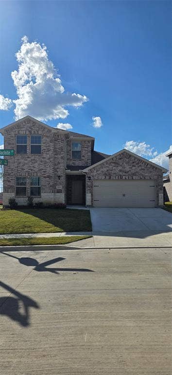 3904 Malachite Drive, Celina, TX 75009 Two-story brick exterior with stone accents, attached two-car garage, concrete driveway, and a front lawn