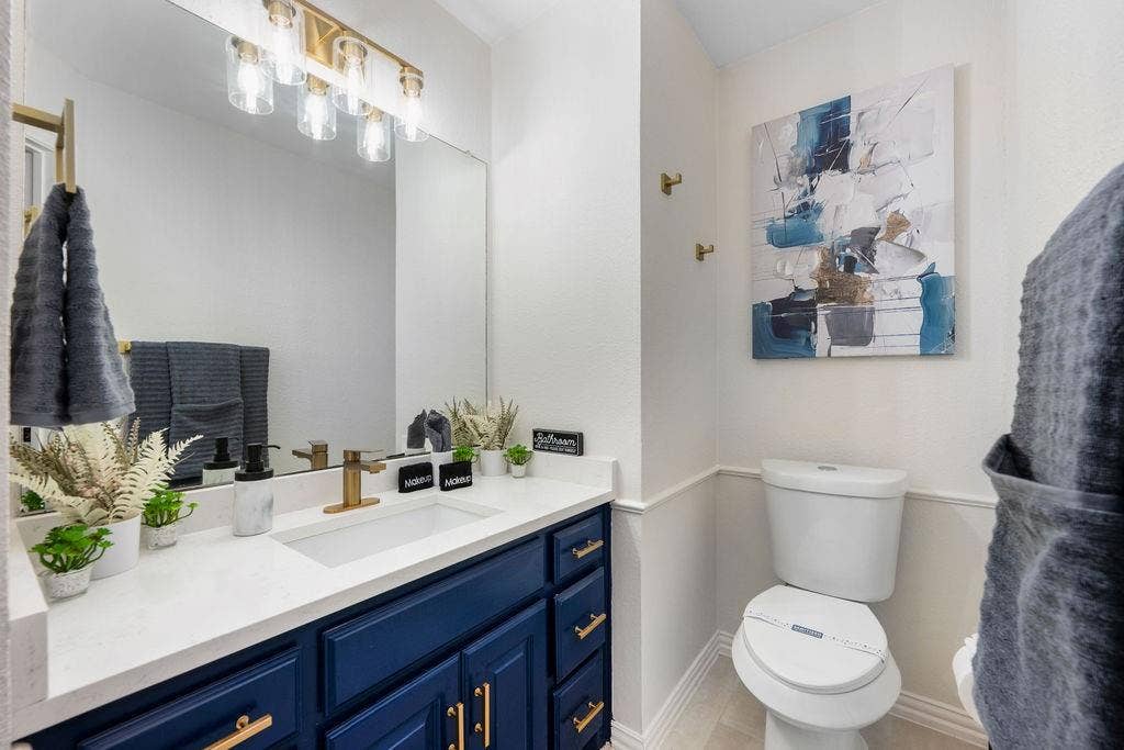 2007 Hill Haven Circle, Richardson, TX 75081 Single vanity with a white countertop and integrated sink, gold-finish faucet, and blue cabinetry with gold-finish hardware