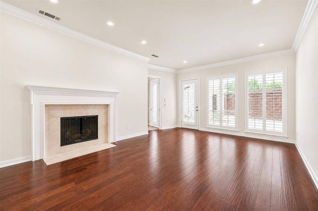 4612 Saxon Drive, Plano, TX 75093 Hardwood flooring, recessed lighting, crown molding, fireplace with hearth, and multiple windows with plantation shutters