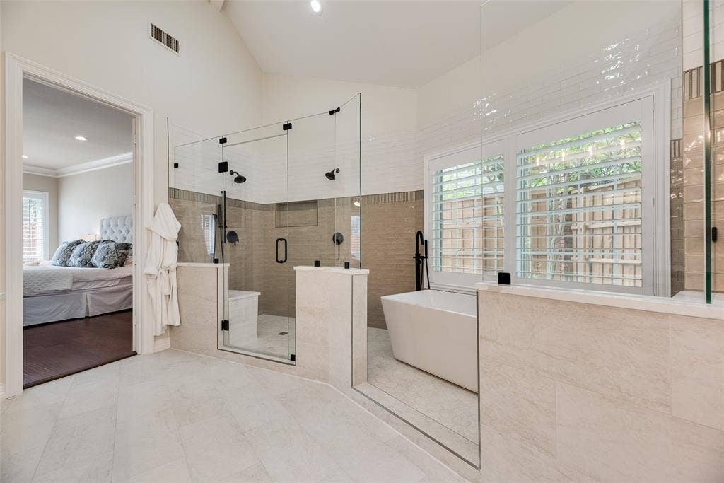 4612 Saxon Drive, Plano, TX 75093 Spacious bathroom featuring a freestanding tub, glass-enclosed shower with dual showerheads, and light-toned tile flooring