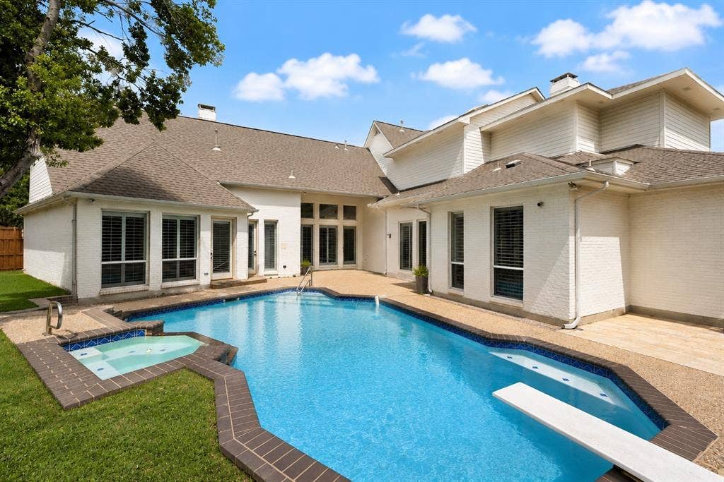4612 Saxon Drive, Plano, TX 75093 Exterior featuring a multi-level roofline, a swimming pool with a diving board, and an integrated spa