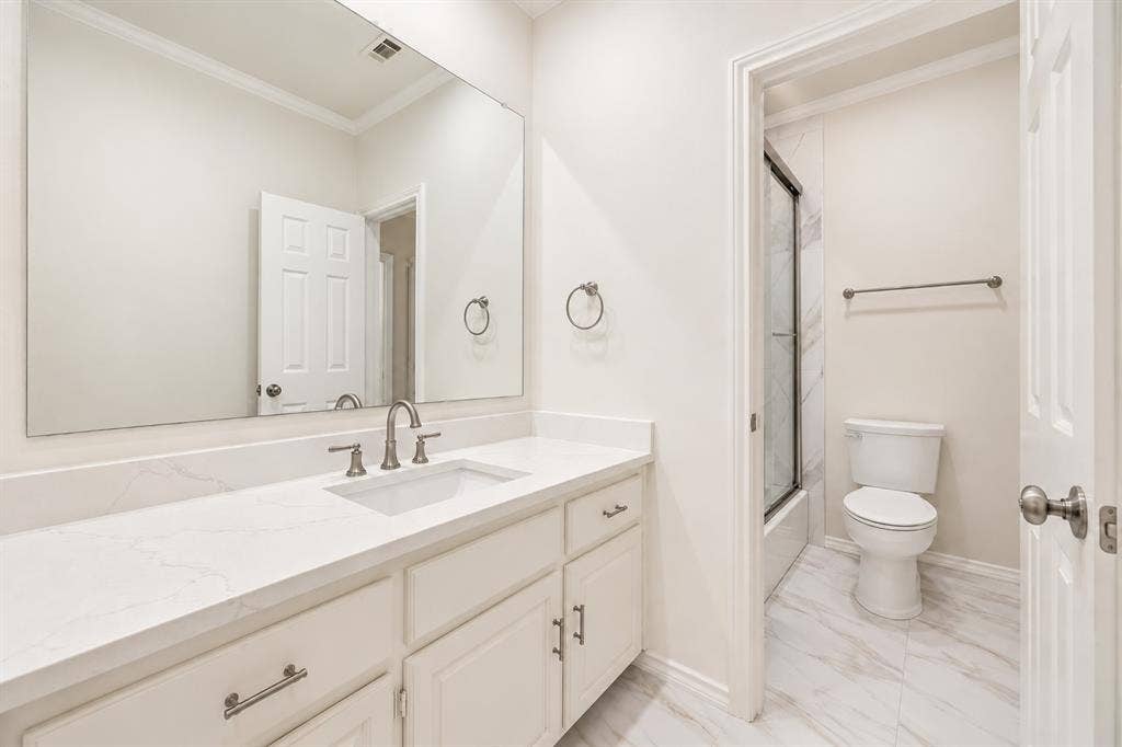 4612 Saxon Drive, Plano, TX 75093 Vanity with a white countertop and undermount sink, brushed nickel faucet, large wall mirror, and white cabinetry