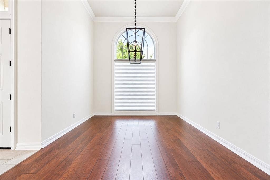 4612 Saxon Drive, Plano, TX 75093 Arch-top window with layered shades, dark wood-finish flooring, and crown molding
