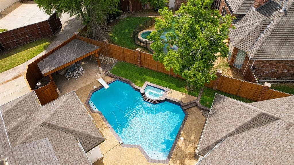 4612 Saxon Drive, Plano, TX 75093 Backyard featuring a swimming pool with integrated spa, diving board, covered patio, privacy fencing, and manicured lawn