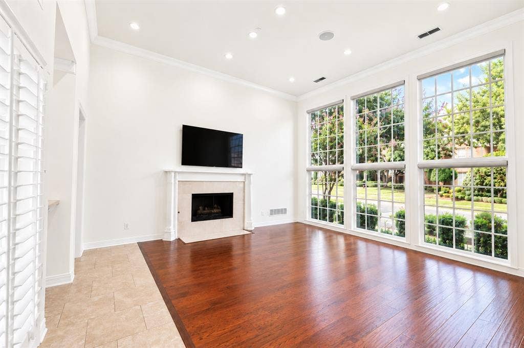 4612 Saxon Drive, Plano, TX 75093 High ceilings with recessed lighting, a built-in fireplace with a stone surround, rich wood-finish flooring, and large picture windows with grids