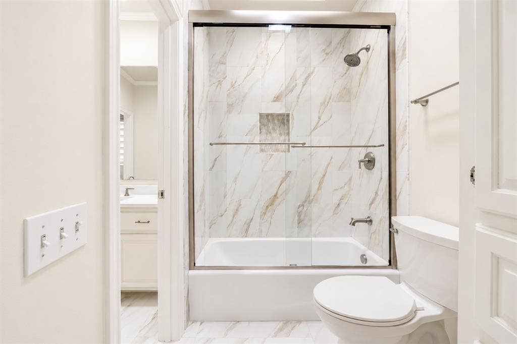 4612 Saxon Drive, Plano, TX 75093 Tub and shower combination with glass enclosure, tile surround, and brushed nickel fixtures
