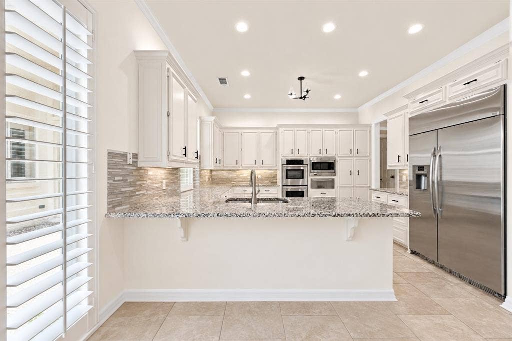 4612 Saxon Drive, Plano, TX 75093 Kitchen featuring extensive white cabinetry, granite countertops, stainless steel appliances, tile flooring, and recessed lighting