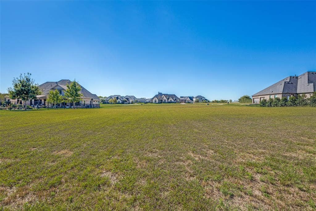 C-14 Waterstone Estates, McKinney, TX 75071 Expansive green space featuring a natural grass lawn, surrounded by residential structures, under a clear blue sky