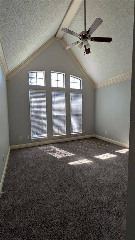 Vaulted ceiling featuring a ceiling fan, light gray wall paint, and gray carpet flooring