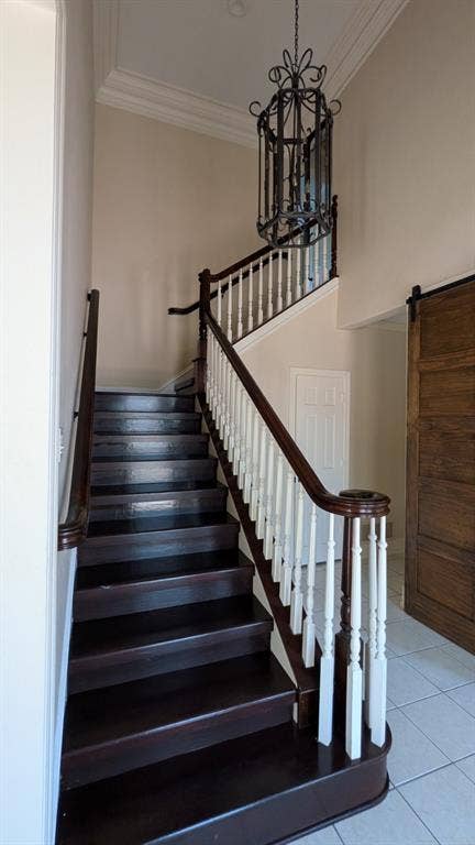 Two-story entry featuring a dark wood-finish staircase with white balusters, an ornate iron chandelier, and a wood-finish barn door