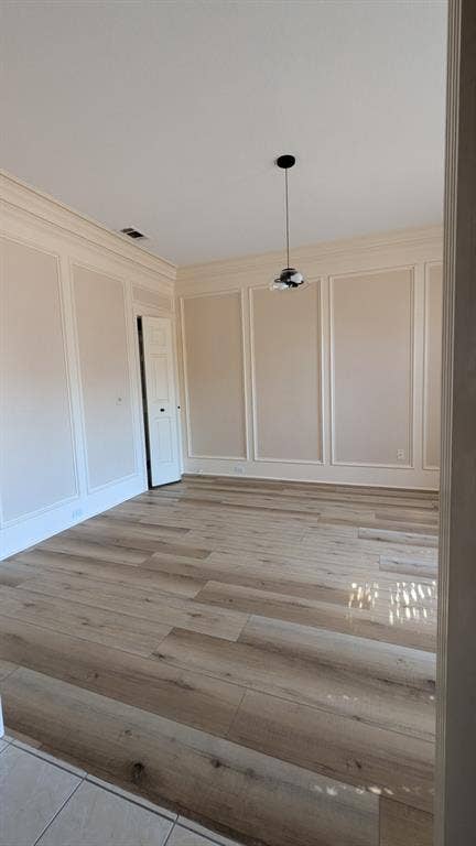 Wood-finish flooring, recessed lighting, crown molding, paneled walls, and a contemporary pendant light fixture