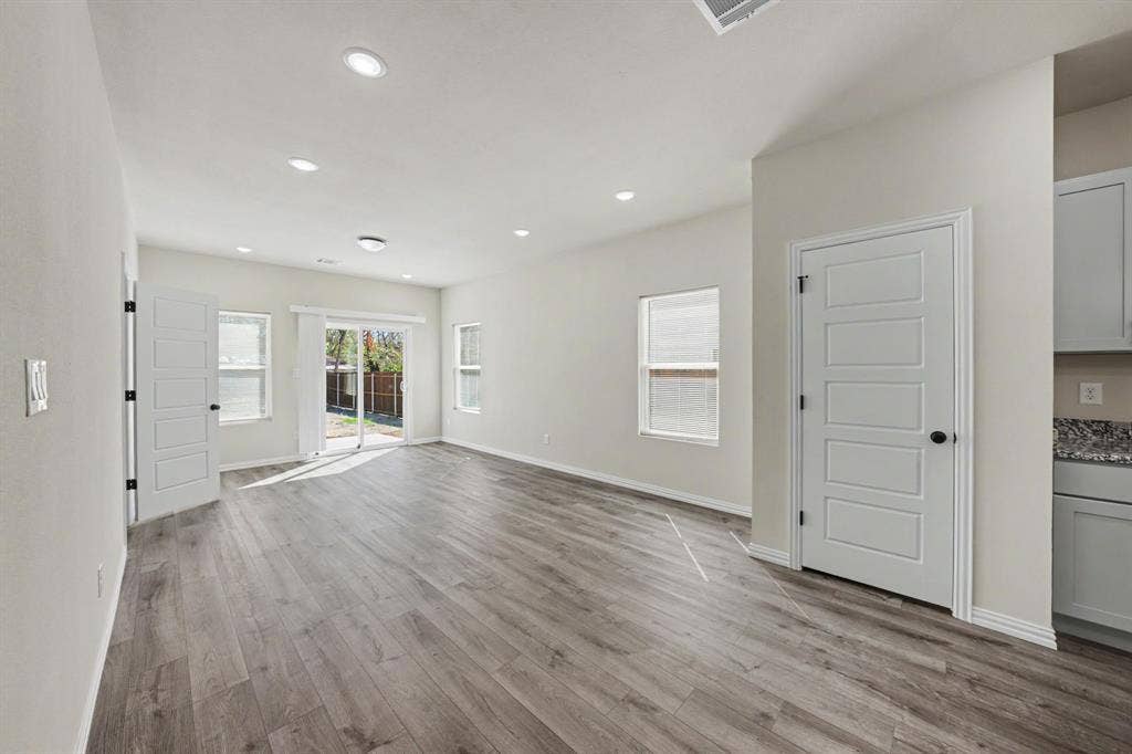 Recessed lighting, wood-finish flooring, sliding glass door, multiple windows, and white cabinetry