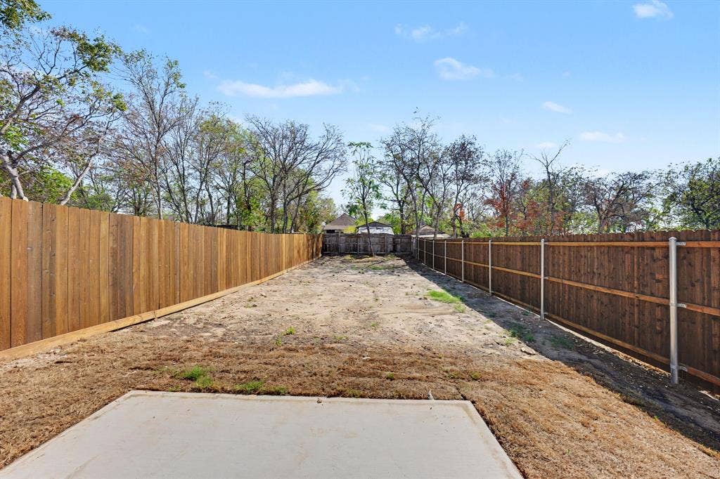 Expansive yard featuring a concrete pad and wood fencing