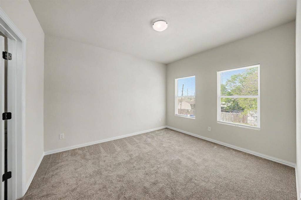 Room featuring light gray carpet, two windows, and a flush mount ceiling light fixture