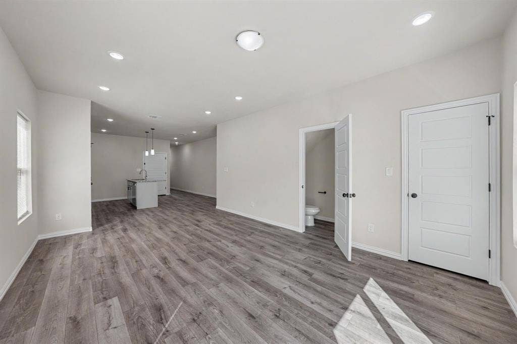 Open-concept layout featuring wood-finish flooring, recessed lighting, white interior doors, and a kitchen island with pendant lighting