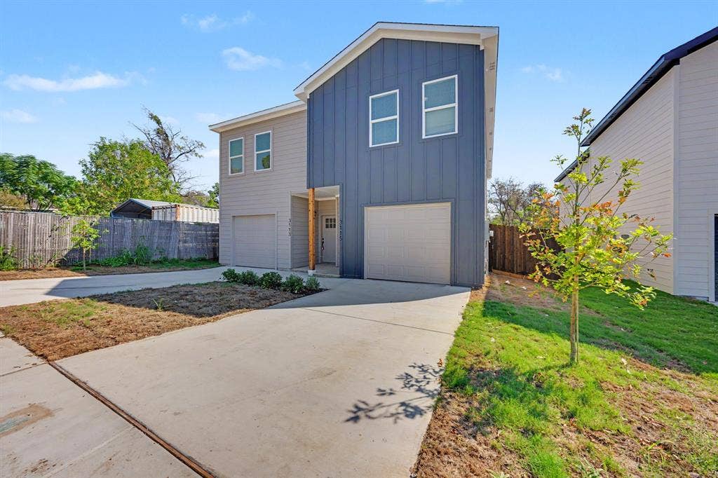 Modern exterior with board and batten siding, two-car garage, concrete driveway, and front landscaping