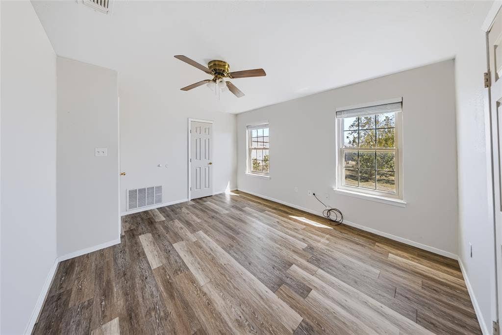 560 Green Acres Road, Weatherford, TX 76088 Wood-finish flooring with white walls, dual windows, and a ceiling fan with integrated lighting