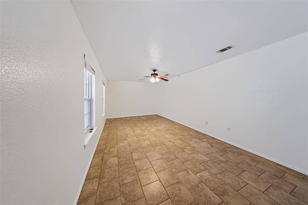 560 Green Acres Road, Weatherford, TX 76088 Spacious room featuring tile flooring, neutral wall tones, multiple windows, and a ceiling fan