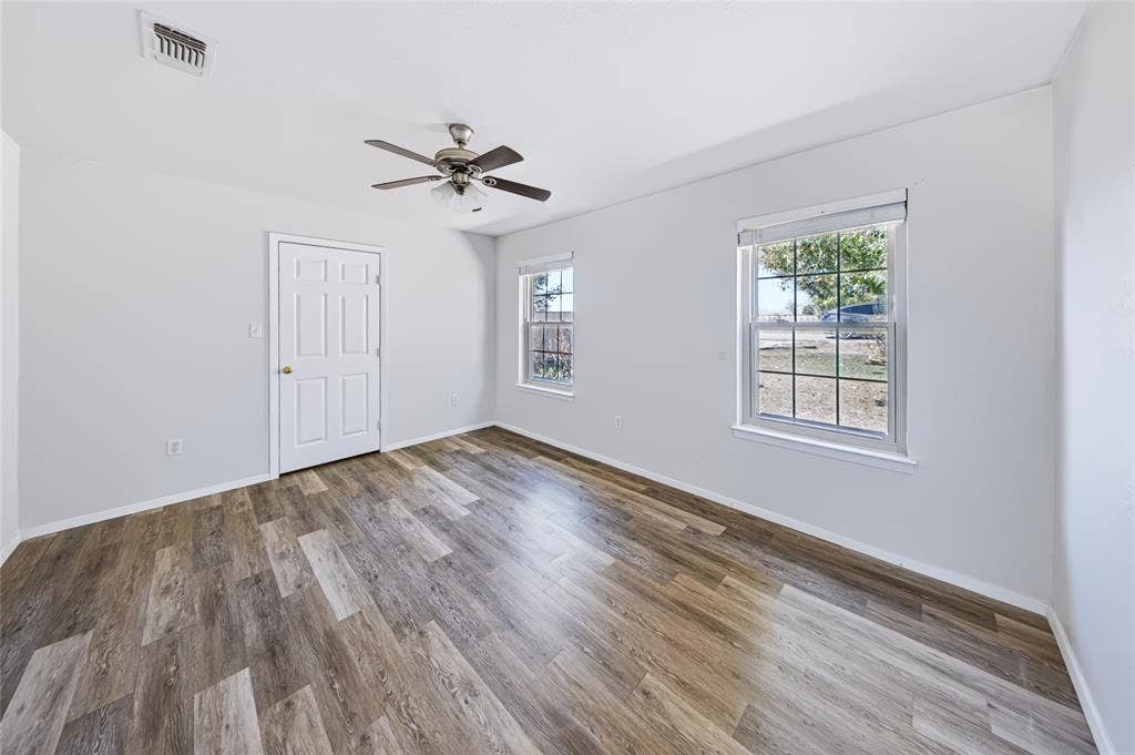 560 Green Acres Road, Weatherford, TX 76088 Wood-finish flooring, white paneled door, two windows with grilles, and a ceiling fan with integrated lighting