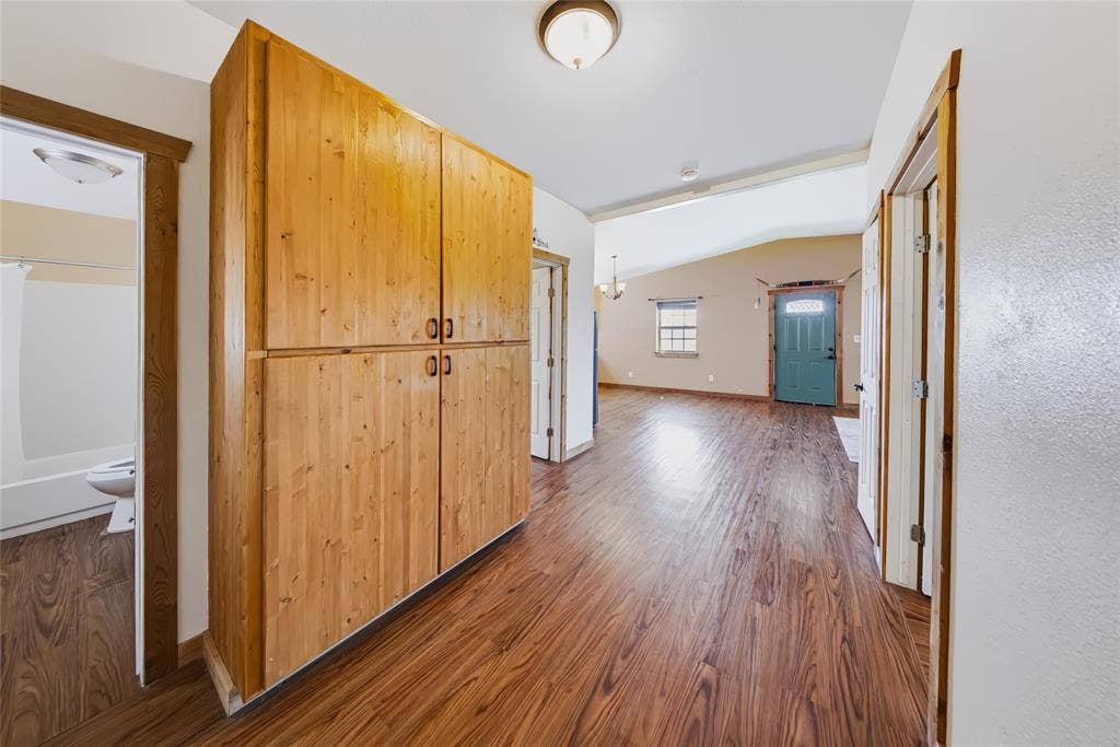 560 Green Acres Road, Weatherford, TX 76088 Wood-finish flooring throughout the hallway, featuring a built-in wood-paneled storage cabinet with dark hardware