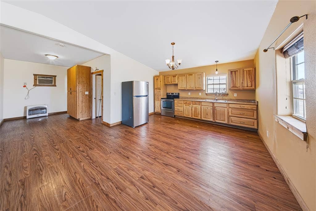 560 Green Acres Road, Weatherford, TX 76088 Spacious open-concept living area featuring wood-finish flooring, natural wood cabinetry, and stainless steel appliances