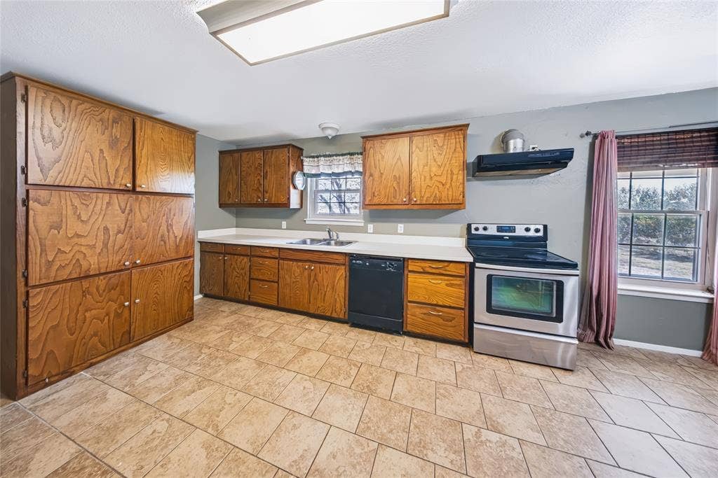 560 Green Acres Road, Weatherford, TX 76088 Kitchen featuring wood cabinetry, light-toned countertops, a stainless steel electric range, and tile flooring