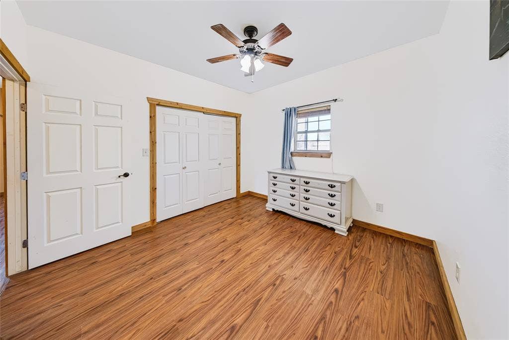 560 Green Acres Road, Weatherford, TX 76088 Wood-finish flooring, white paneled doors, ceiling fan with light fixture, and wood trim details