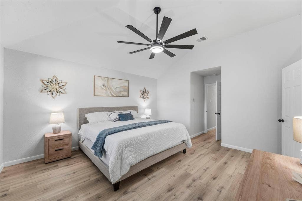 Vaulted ceiling with a contemporary ceiling fan, wood-finish flooring, and white paneled door