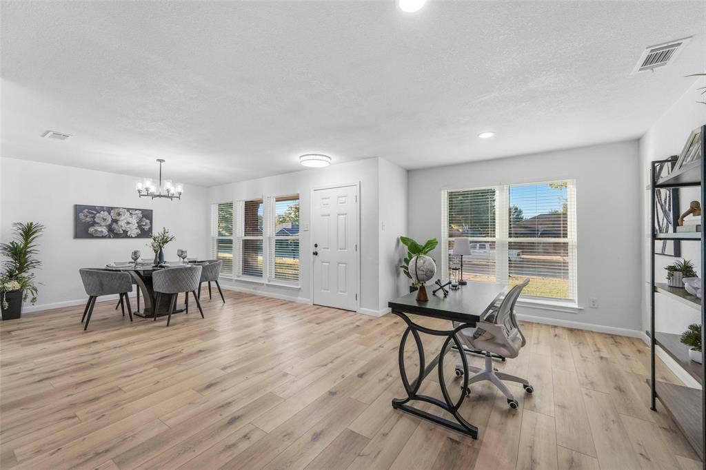 Spacious open-concept interior featuring light wood-finish flooring, multiple large windows, and recessed lighting