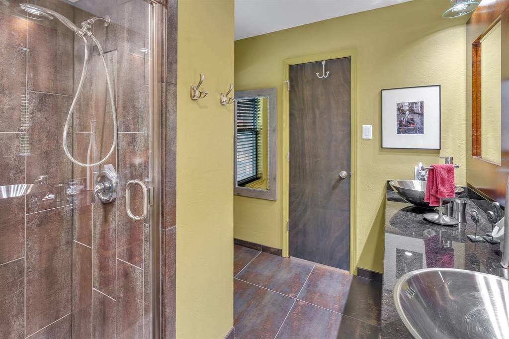 Upstairs bathroom with clear glass walk in shower and double stainless steel sinks.
